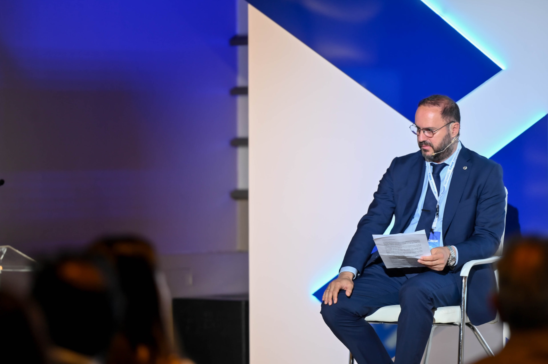 Lavrentios Vasileiadis seated on a conference panel with a headset microphone